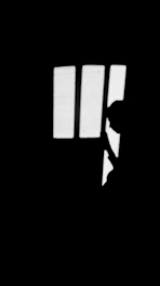 Monochrome still from a short film showing a silhouette against a bright window.