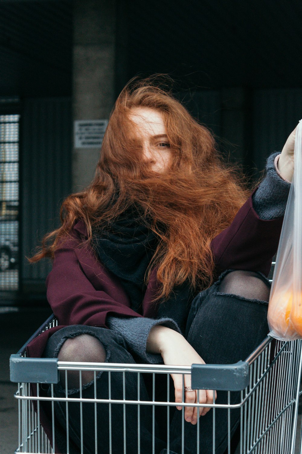 woman sitting on gray shopping cart