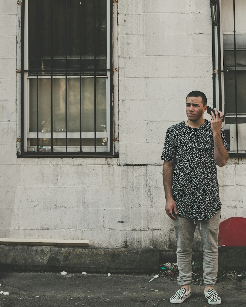 man standing in front of building while holding phone during daytime