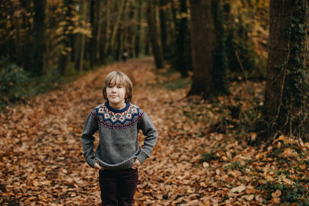 boy standing between tall trees