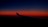 A dark blue sky transitions into a vibrant orange and red horizon, with the silhouette of an airplane wing visible in the foreground.