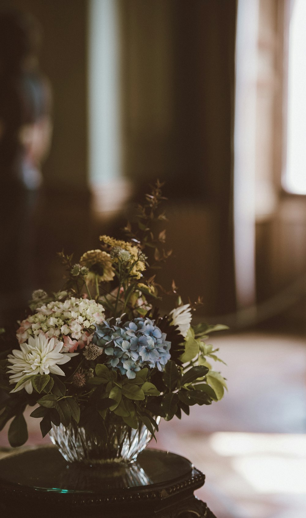 white and blue petaled flower centerpiece on wooden table