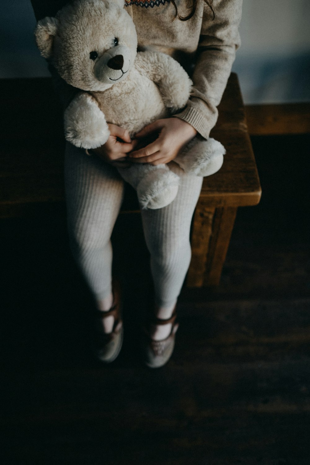 girl holding bear while sitting on bench