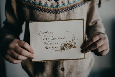 person holding white and brown card christmas card zoom background