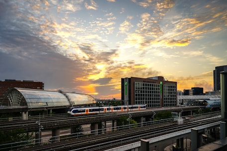 A sleek Acela Express train gliding past a vibrant city skyline at sunset.