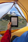 person holding black Amazon Kindle E-Book reader inside tent at daytime