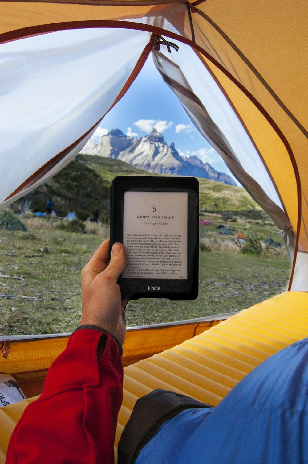 昼間、テントの中で黒いAmazon Kindle電子書籍リーダーを持っている人