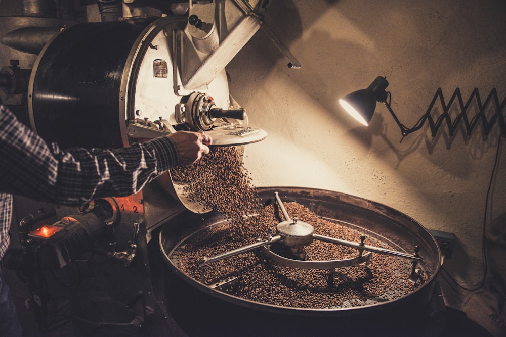 person pouring coffee beans on a machine