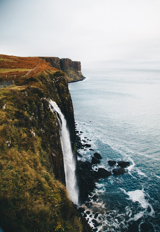 waterfalls in the cliff leading towards the ocean at daytime in Skye United Kingdom
