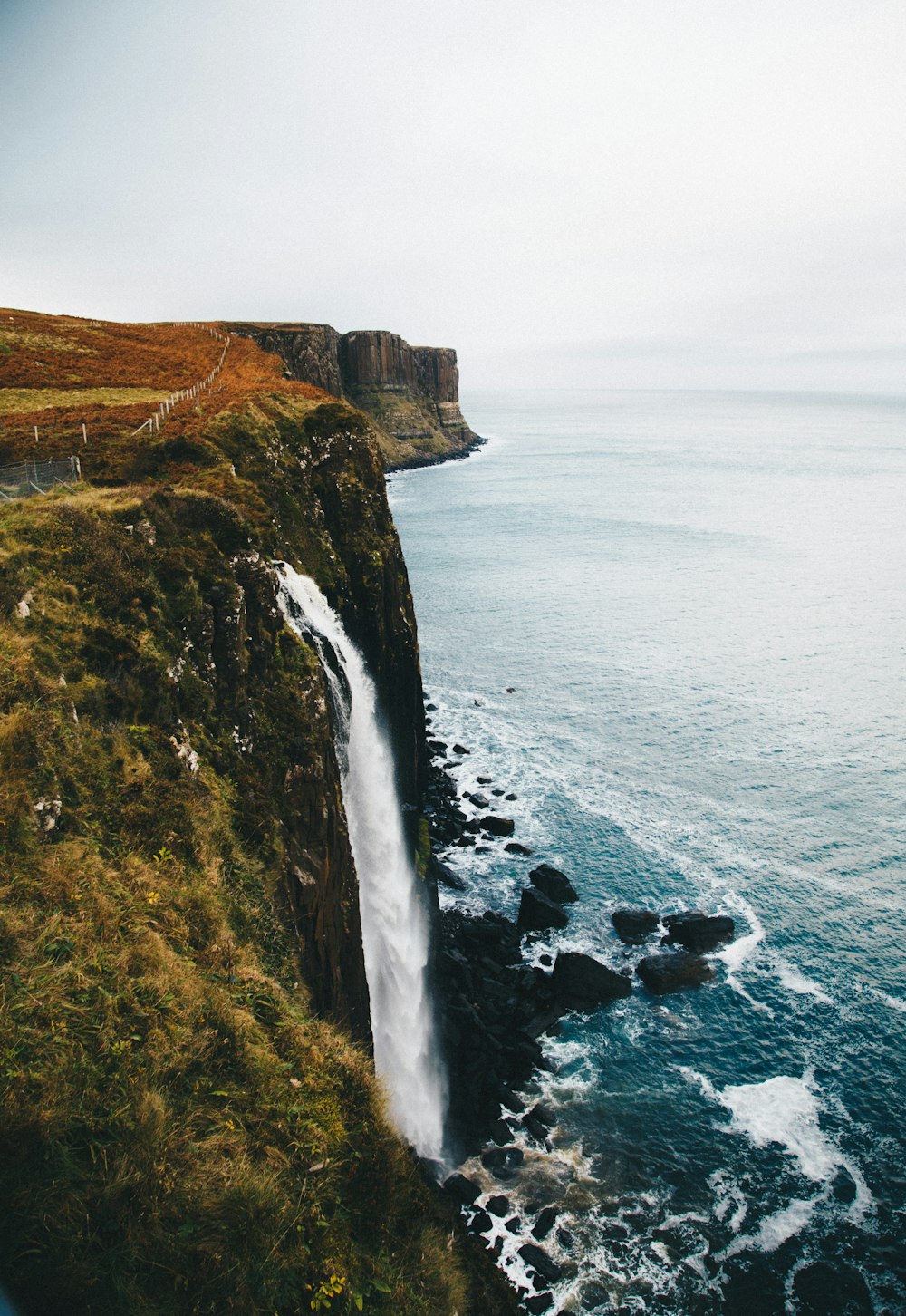 waterfalls in the cliff leading towards the ocean at daytime