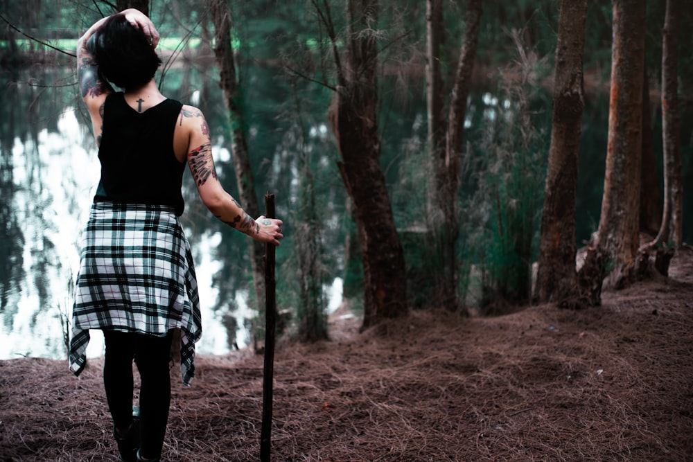 woman standing while holding stick in front of body of water