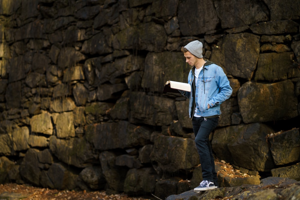 man reading book beside wall