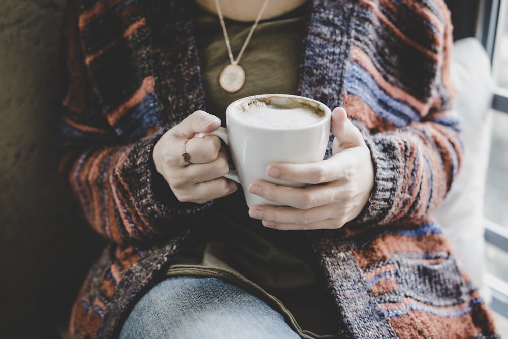 person holding white ceramic cup