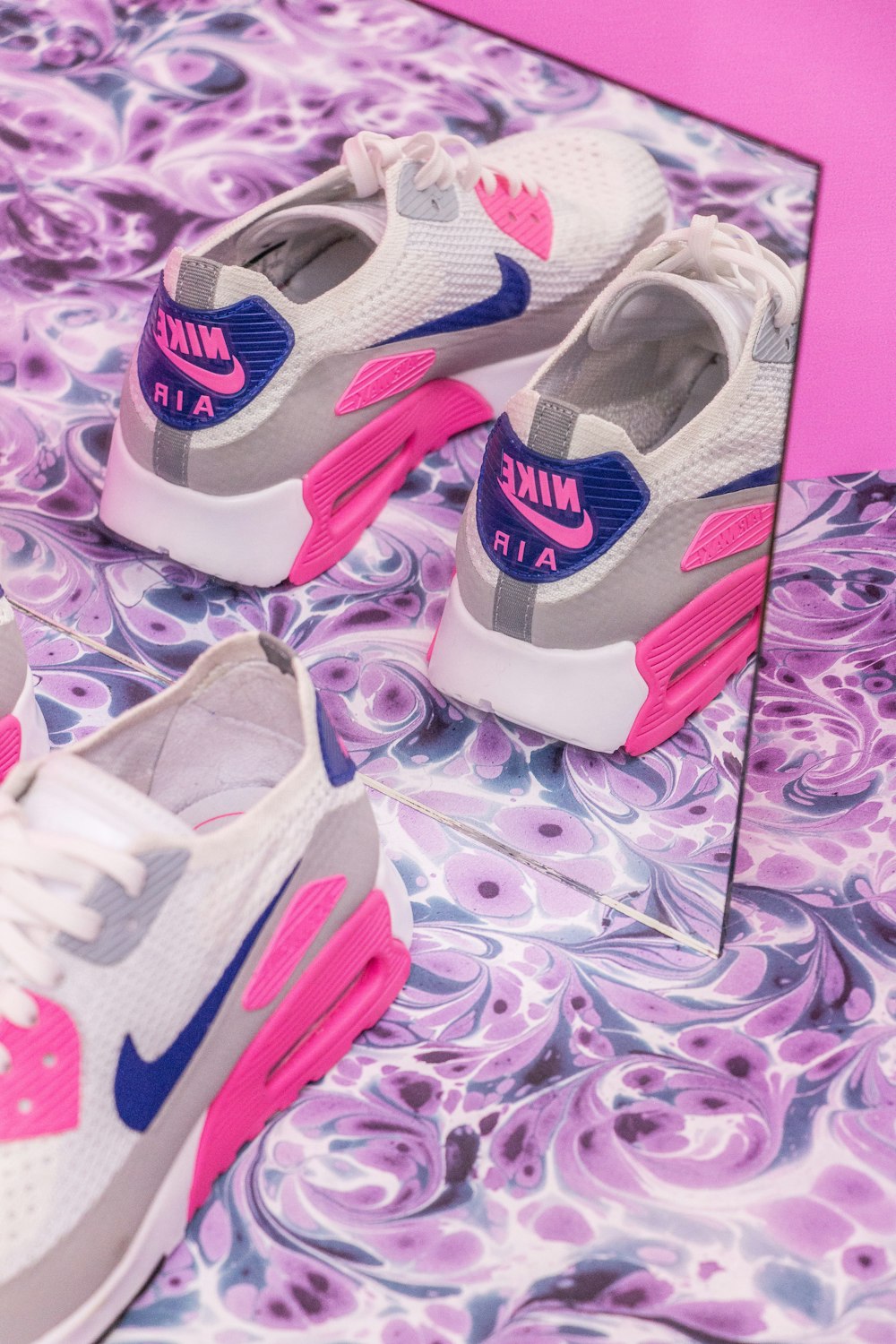 Foto de primer plano par de zapatillas Nike Air Max blancas, grises y rosas frente al espejo