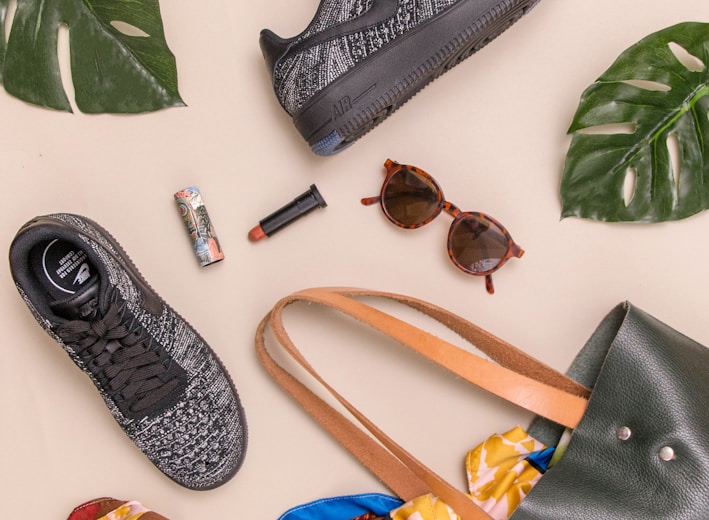 photo of bag, sneakers, and sunglasses on beige surface