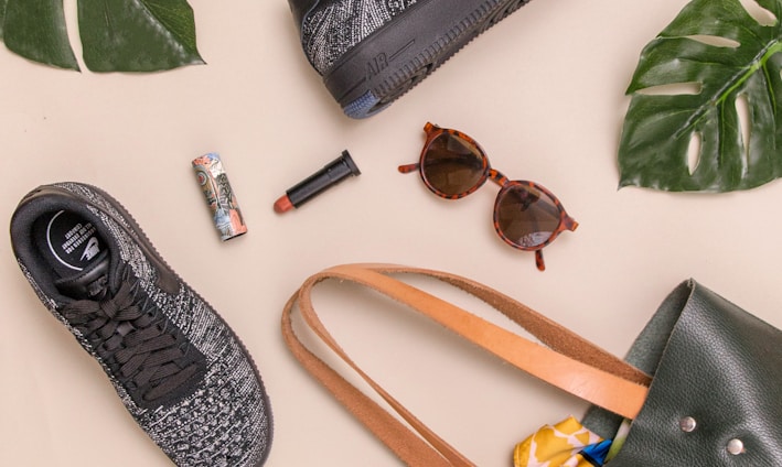 photo of bag, sneakers, and sunglasses on beige surface