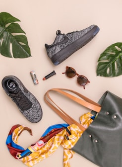 photo of bag, sneakers, and sunglasses on beige surface