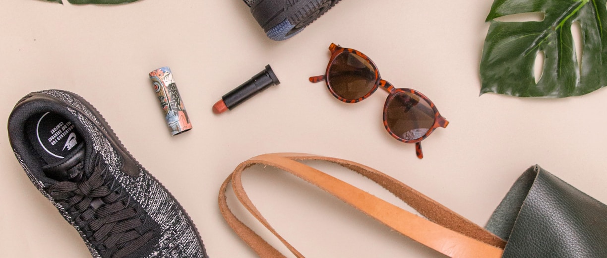 photo of bag, sneakers, and sunglasses on beige surface