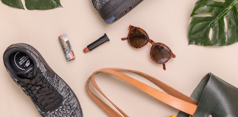 photo of bag, sneakers, and sunglasses on beige surface