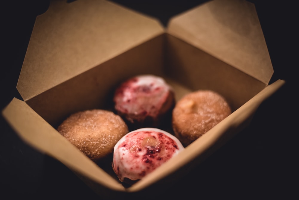 Selektive Fokusfotografie von vier Donuts in braunem Karton