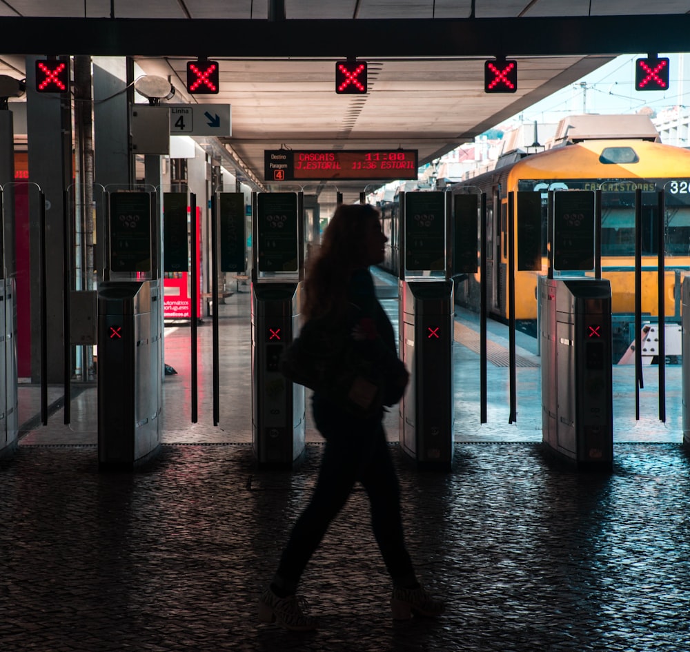 silhouette of woman walking on train station