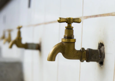 Close-up of a craftsman’s hands holding a sleek chrome tap against a minimal white background.