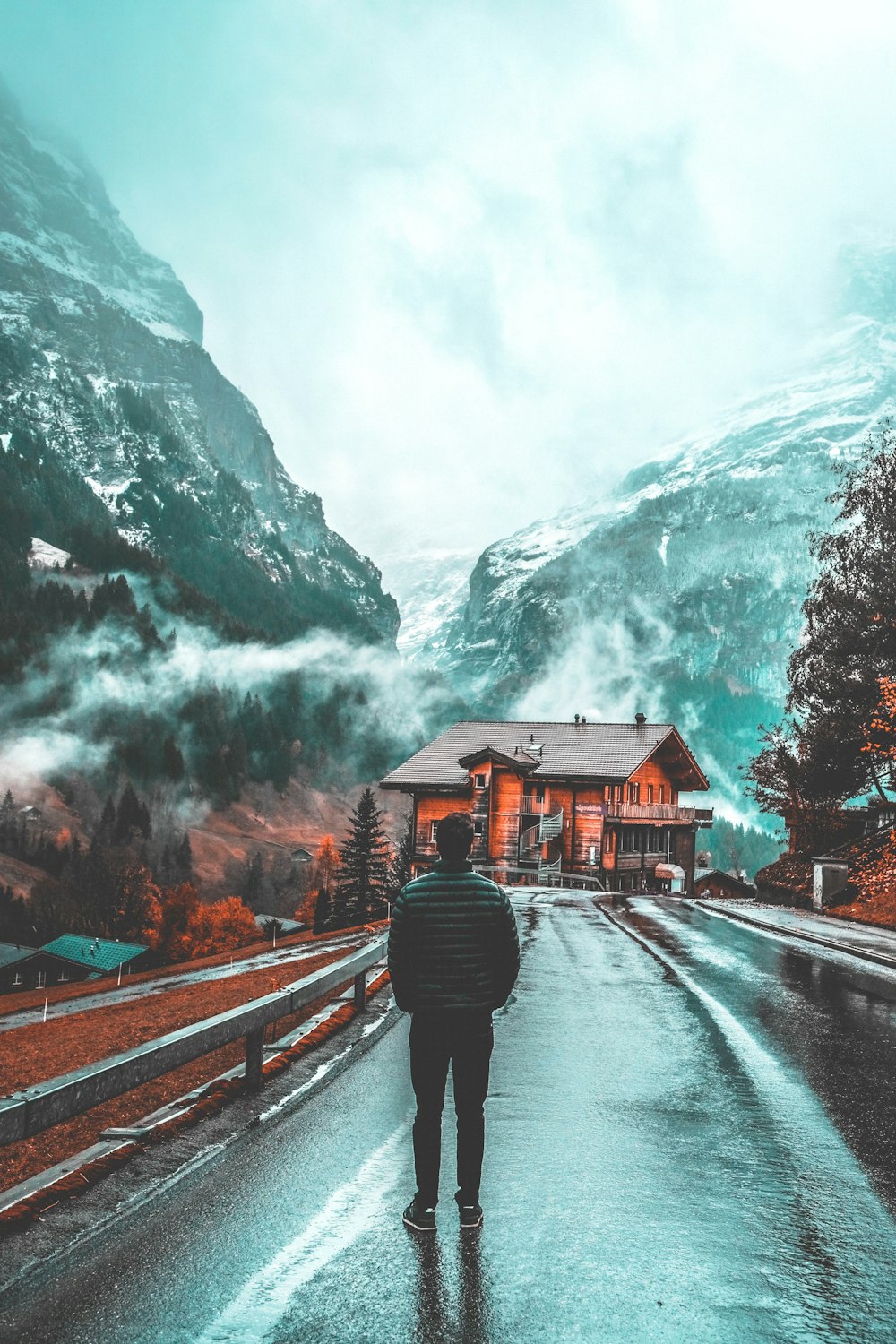 man standing on concrete pavement facing wooden house