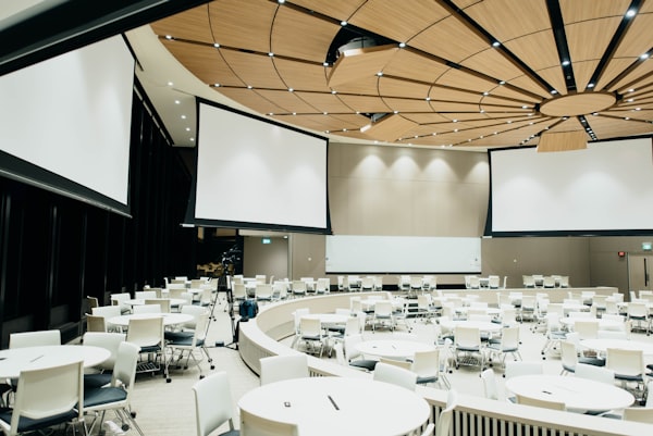 Empty networking room for a museum conference with several tables, chairs, and presentation screens