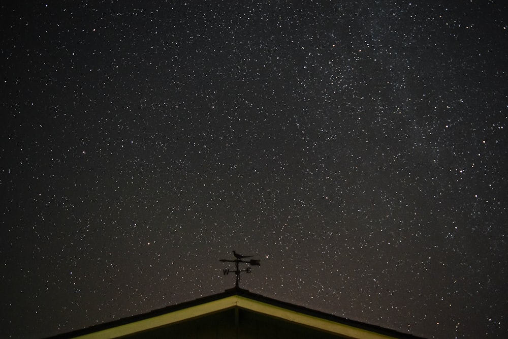 the night sky with stars above a roof