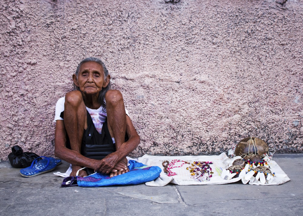 a man sitting on the ground next to a wall