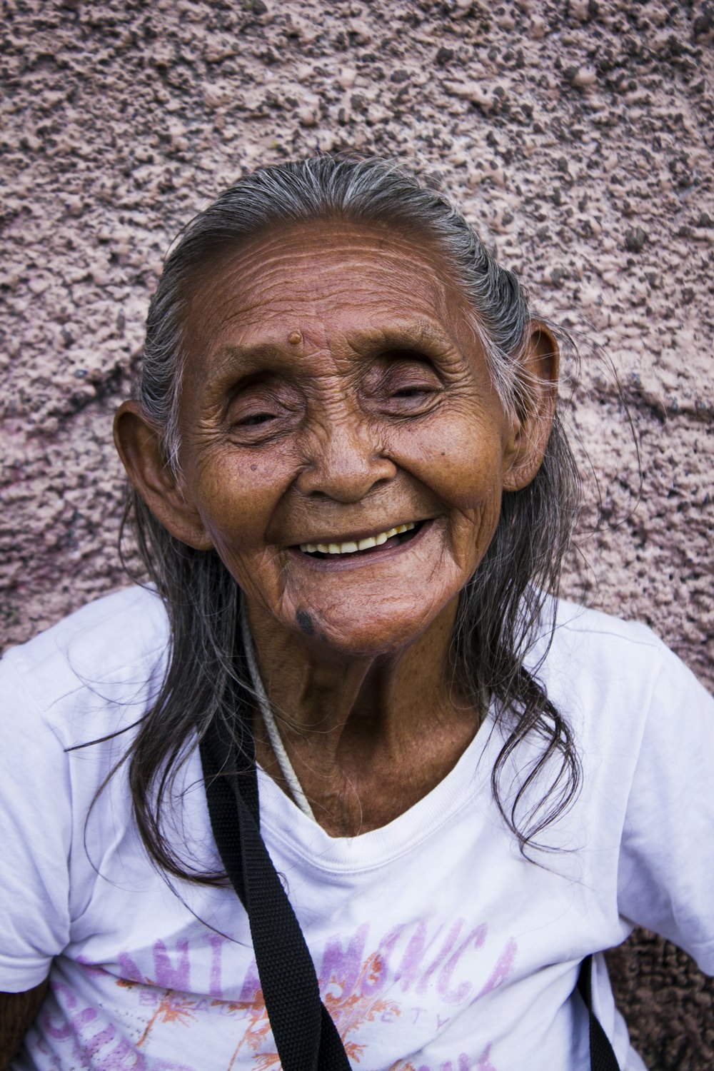 mulher sorrindo enquanto se apoia na parede cinza