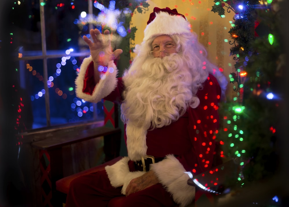 Papai Noel sentado ao lado de árvore iluminada