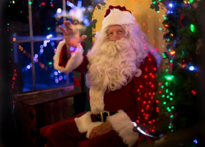 santa claus sitting beside lit tree santa zoom background