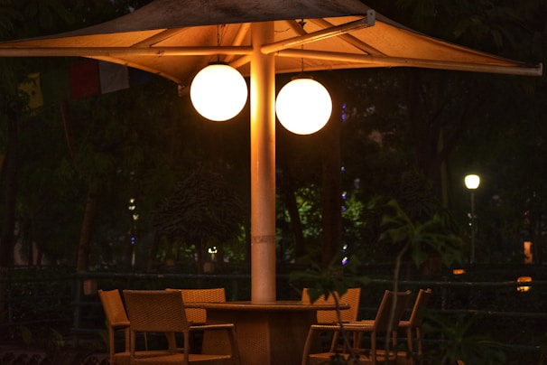A round rattan patio dining table set for an evening meal with soft outdoor lighting.