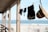 A clothesline hangs along the edge of a wooden porch with garments and a straw hat clipped on it. The background reveals a sandy beach and the ocean under a partly cloudy sky.