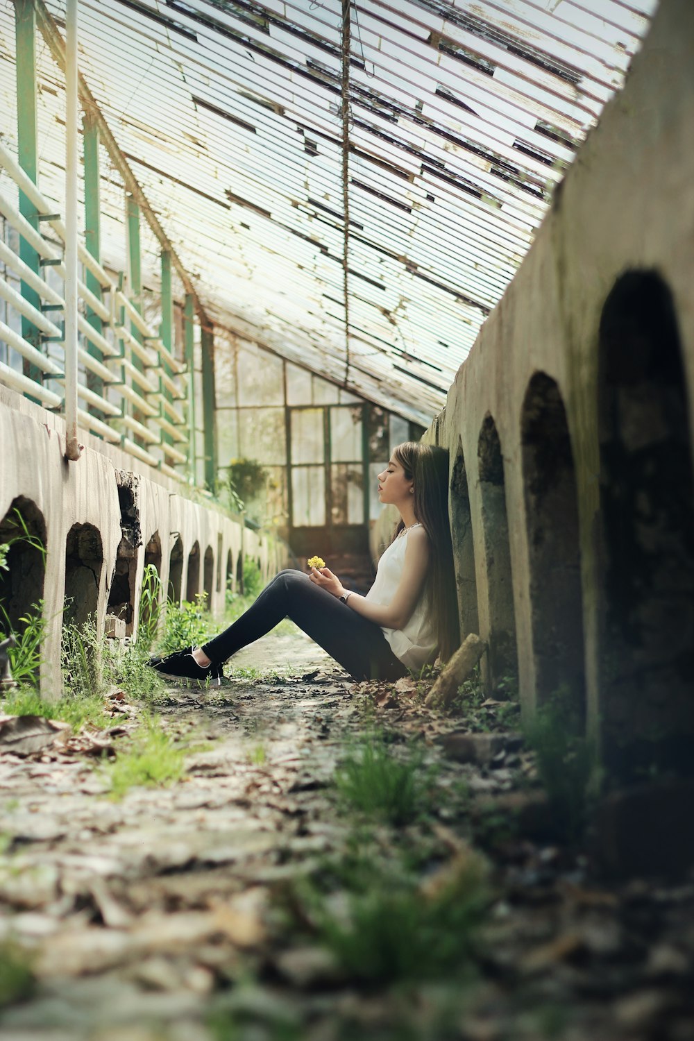 woman sitting between concrete fence at daytime