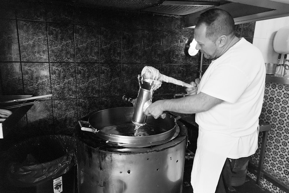 fotografia em tons de cinza do homem segurando o recipiente cinza dentro do recipiente