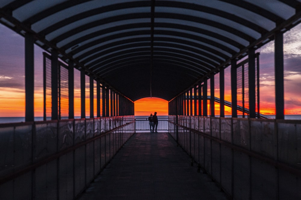 silhouette photo of persons on foot bridge