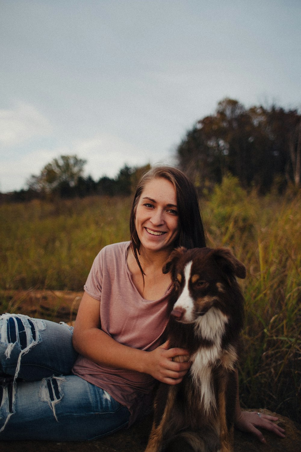 woman sitting beside a black and white dog