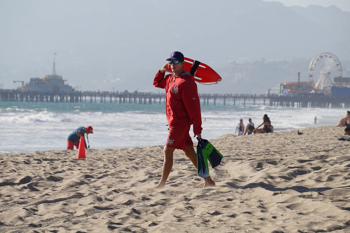Los Angeles'ta Santa Monica sahilinde kumsalda yürüyen cankurtaran