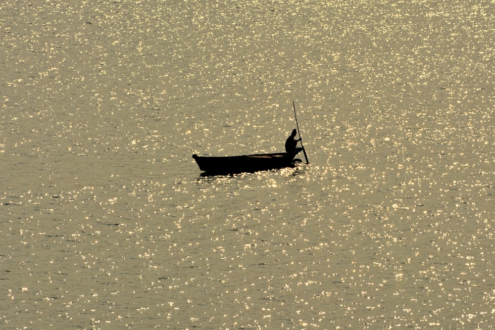 person on boat fishing on body of water