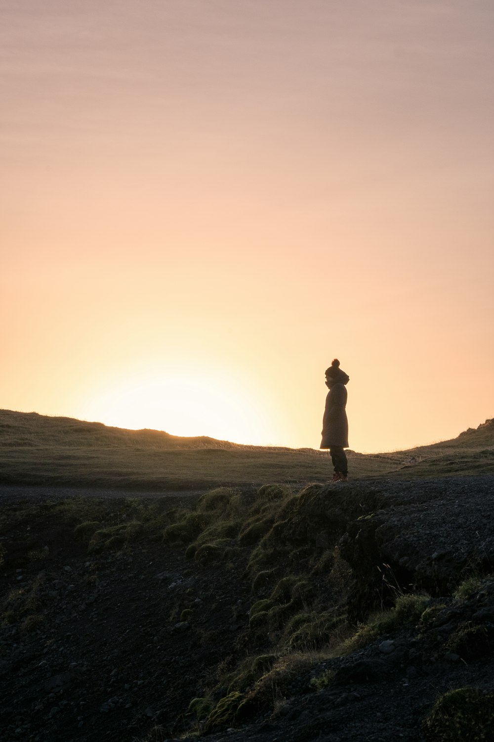 silhouette of person standing on hill during golden hour