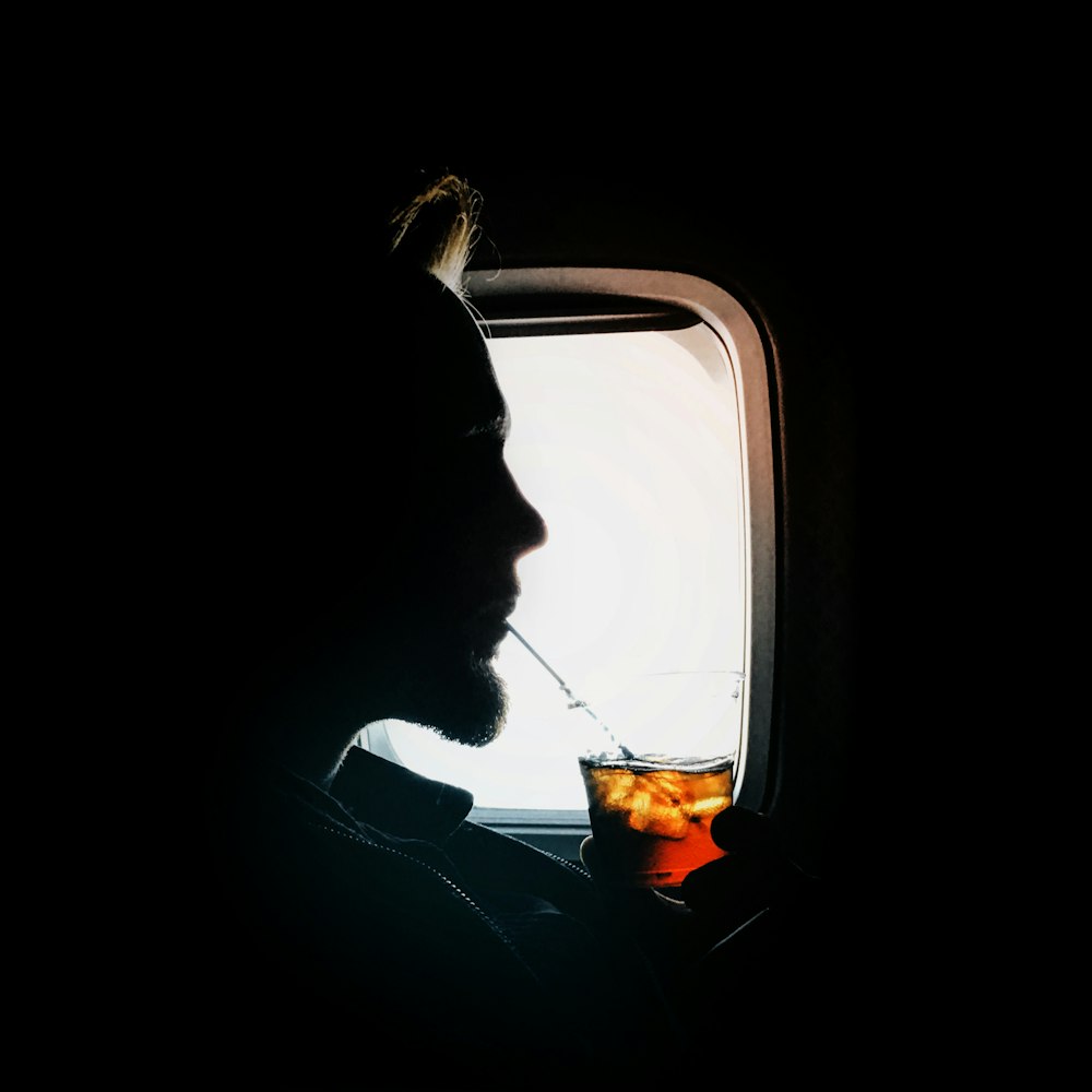 man sipping drink beside window