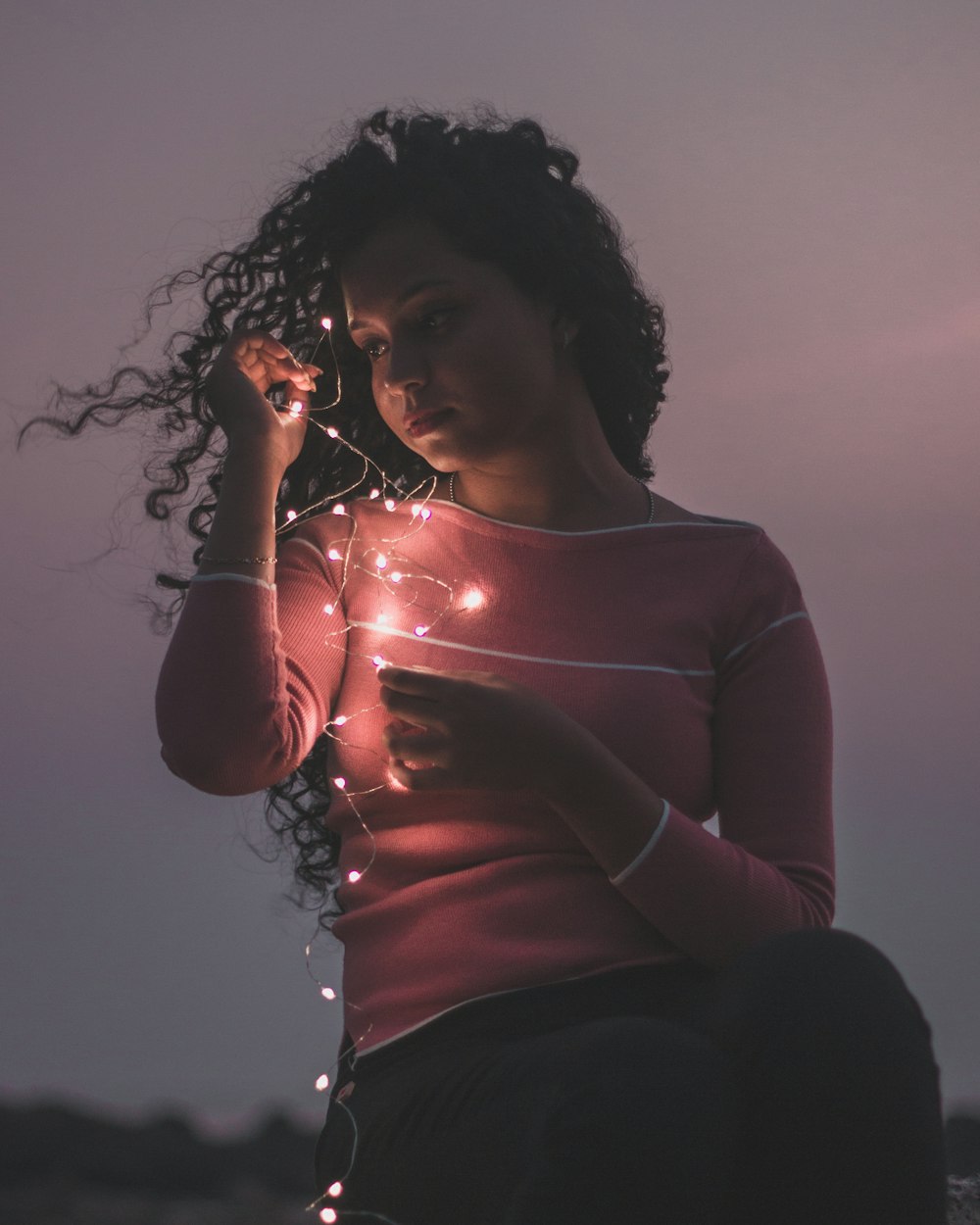 woman holding string lights