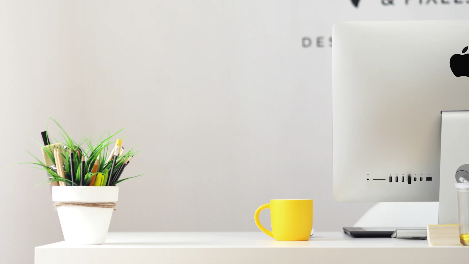 Studio corner with a mug beside an iMac in warm light