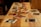 Several printed photographs are scattered across a wooden table. The photographs vary in orientation and depict different scenes or subjects, creating a nostalgic and artistic arrangement. The warm tones of the wood complement the varied colors in the photographs.