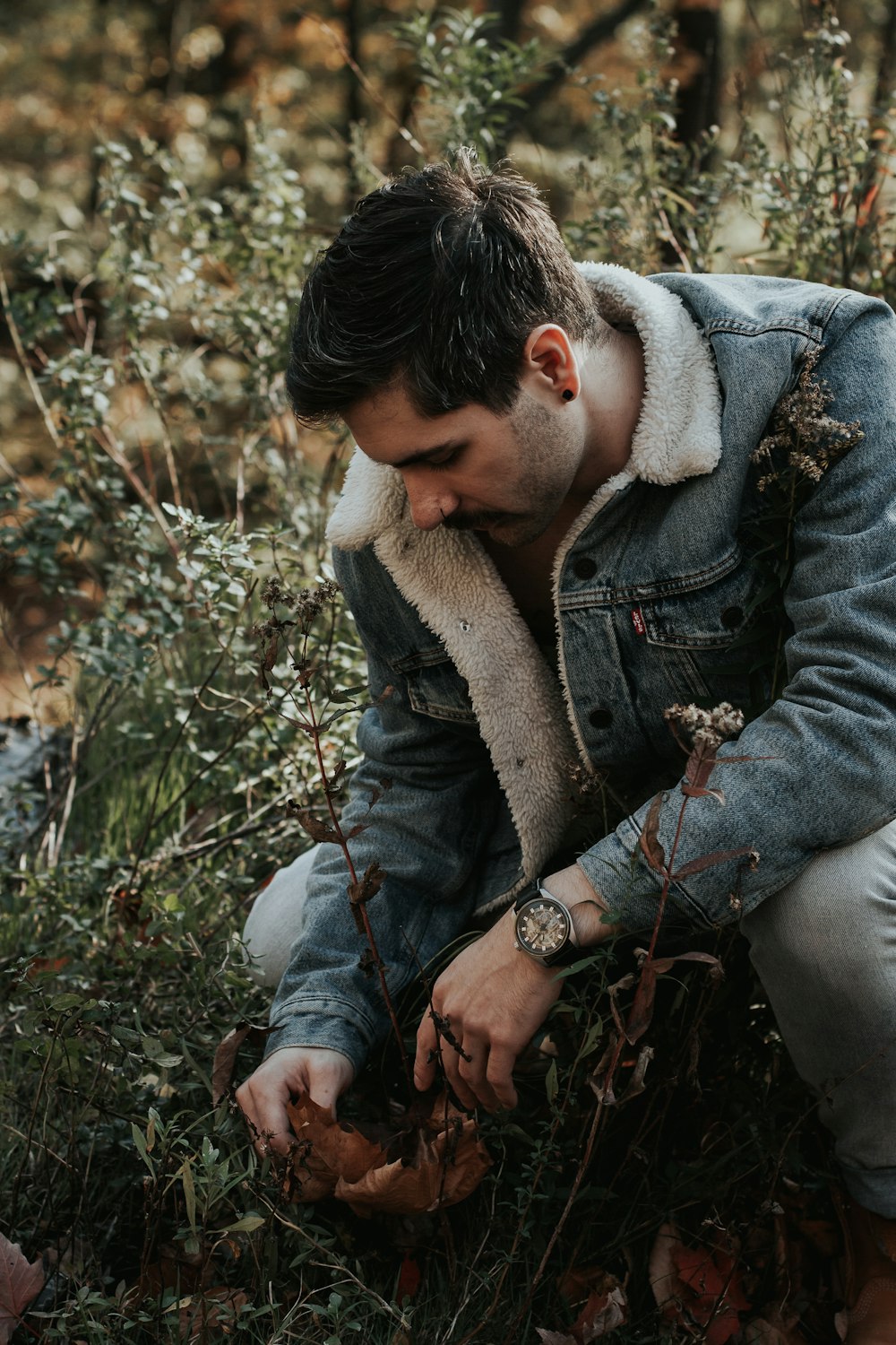 man picking up dried leaves