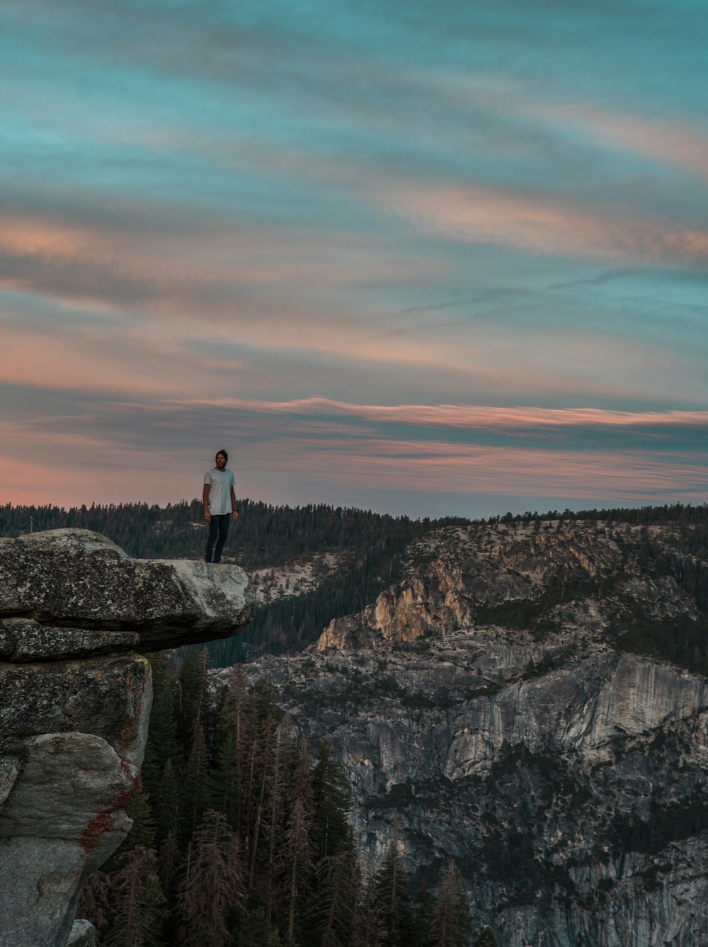 man standing on cliff near mountain