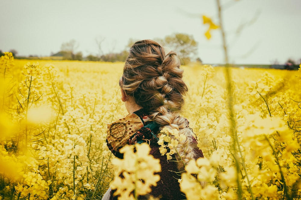 Frau sitzt neben gelben Blumen