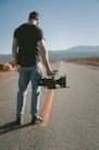 man holding video camera sanding on road